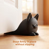 A black anti-slam door stopper wedge shaped like a cat sits on a wooden surface.