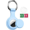 Light blue silicone protective cover for an AirTag with a metal keychain ring and cleaning wipes.