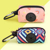 A pink zippered pouch with a black button and a rainbow pattern is shown next to a patterned blue and white bag holder.