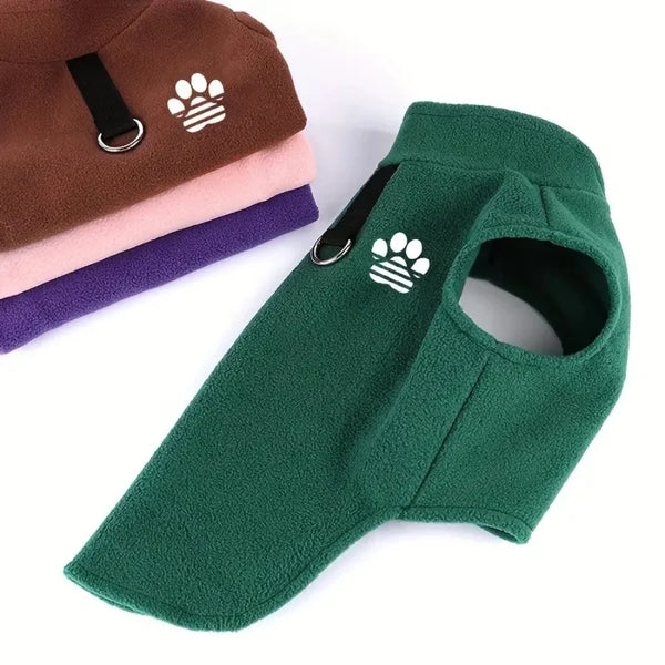 A green fleece dog sweater with a paw print design is shown next to stacked sweaters in brown, pink, and purple.