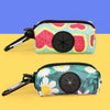 A colorful, patterned pouch designed to hold dog poop, featuring a pink and green fruit design.