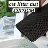 Un tapis à litière noir utilisé dans une boîte à chats, avec de la litière qui s'échappe.