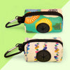 A pair of colorful fabric poop bag holders with black zippers and metal clasps are shown against a light green background.