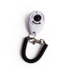 A white pet training clicker with a black cord attached to a metal clasp.