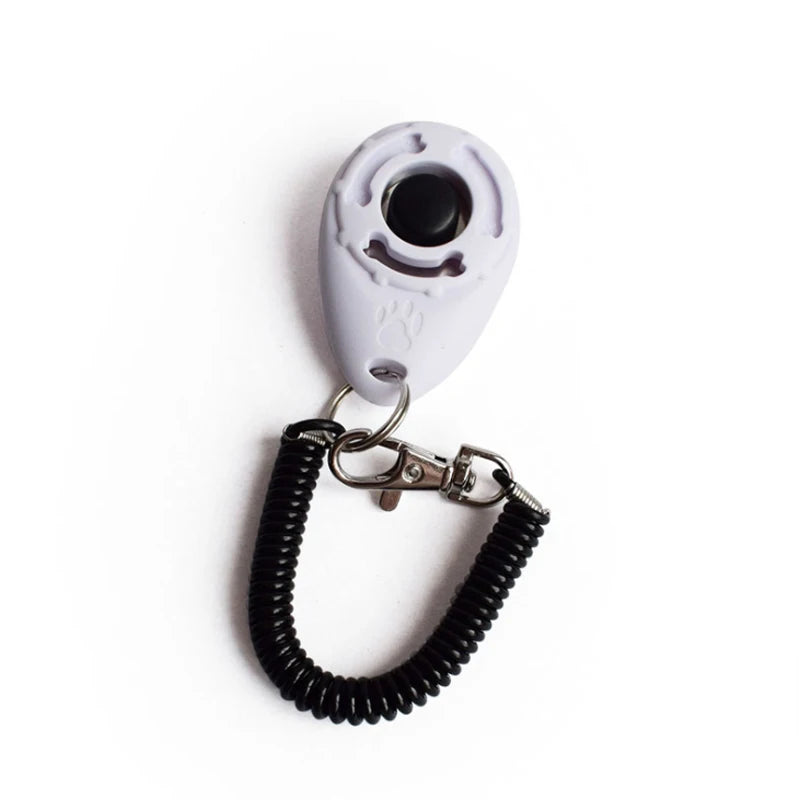 A white pet training clicker with a black cord attached to a metal clasp.