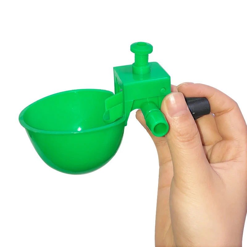 Une main tient un abreuveur de poulet automatique vert avec un bol et un mécanisme de distribution.