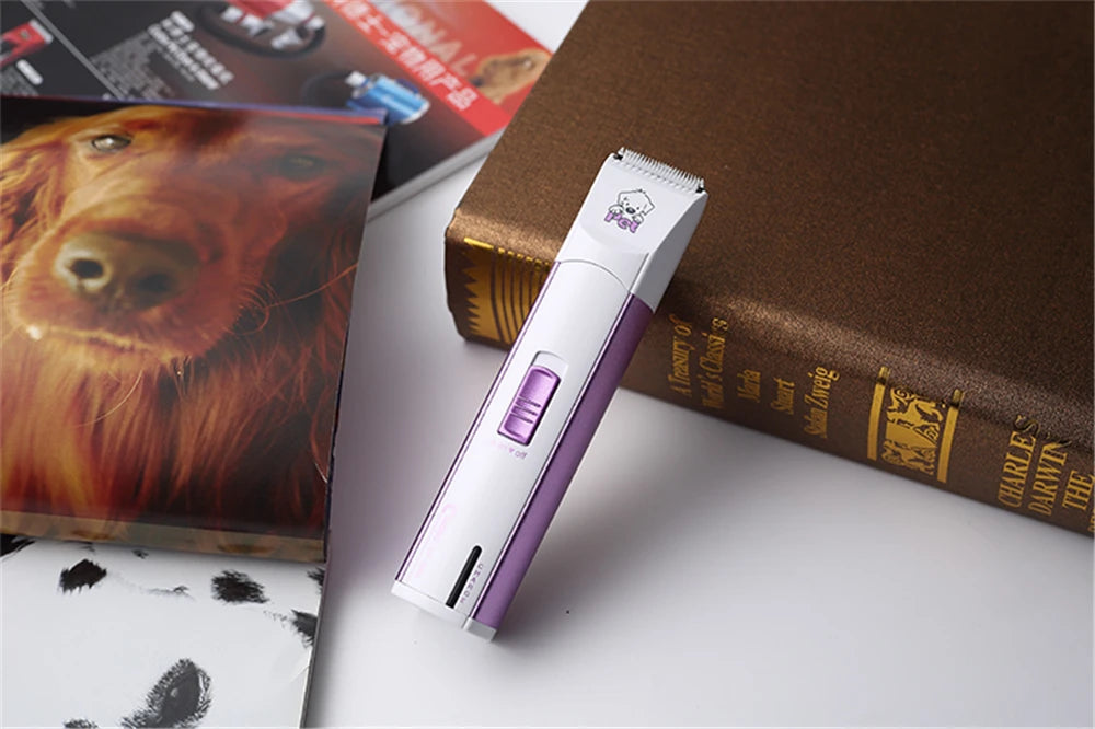 Weißer elektrischer Tierhaartrimmer auf einem braunen Buch neben einem Hundebild.