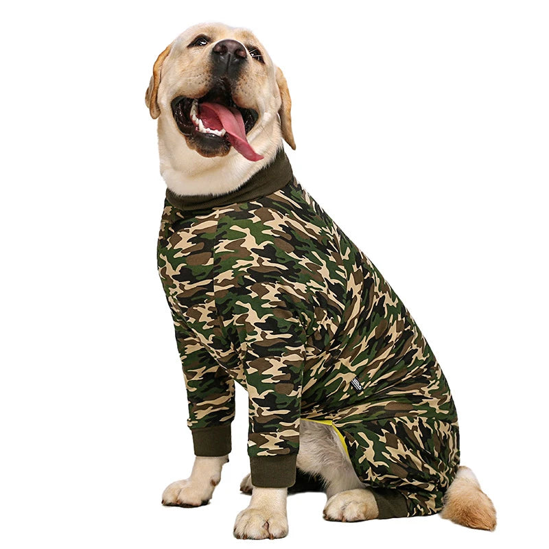 A golden retriever wearing a camouflage print jumpsuit, smiling and tongue out.