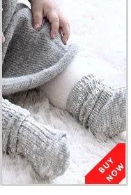 Graue Strickbaby-Socken mit Cartoon-Tierdesign auf weißem flauschigem Fell.