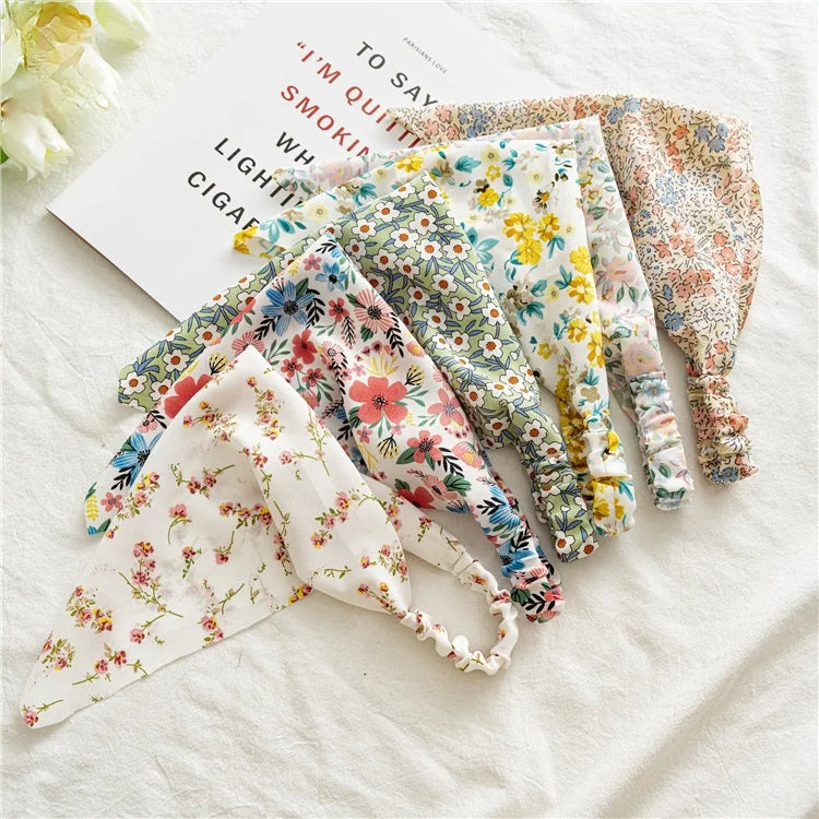 A collection of bohemian paisley triangle head scarves in floral patterns laid out on a white surface.