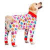 A golden retriever wearing a colorful cartoon animal print jumpsuit with red trim.