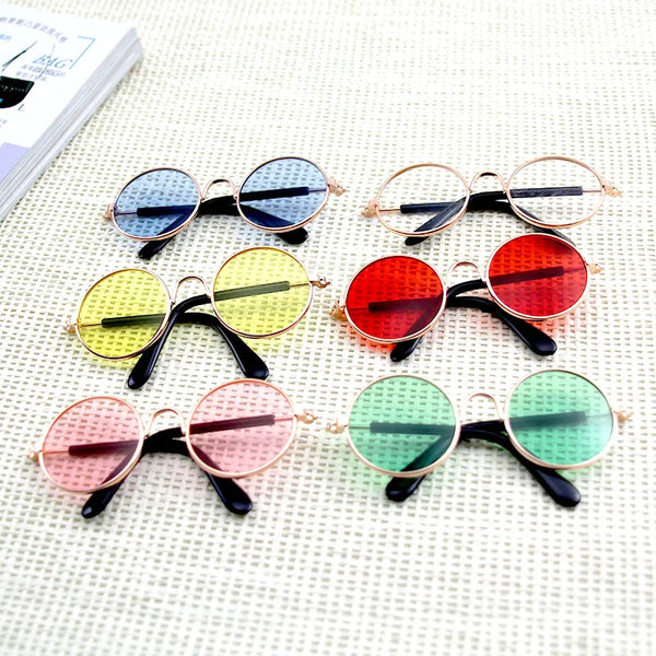 A collection of pet sunglasses for cats and dogs in various colors including blue, black, yellow, red, and green.