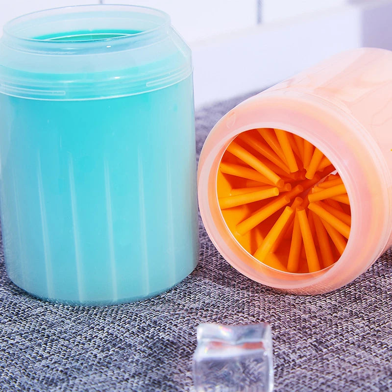 Klare Silikon-Tierpfantrockenbürste mit orangen Borsten neben einem blauen Reinigungbehälter.
