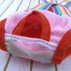 A pink and orange washable physiological dog underwear product is shown on a wooden surface.