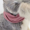 A pink soundproof pet ear muff is placed on the fur of a gray and white dog.