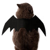 Un chat brun portant un costume d'ailes de chauve-souris noires.
