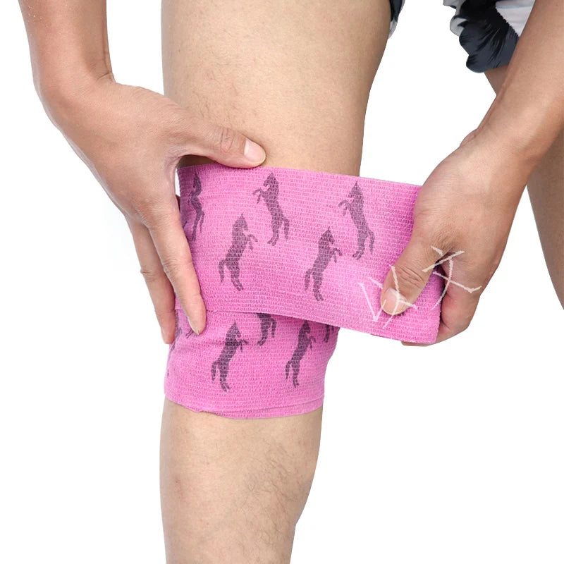 A hand is applying a pink printed self-adhesive elastic bandage tape to a person's leg.