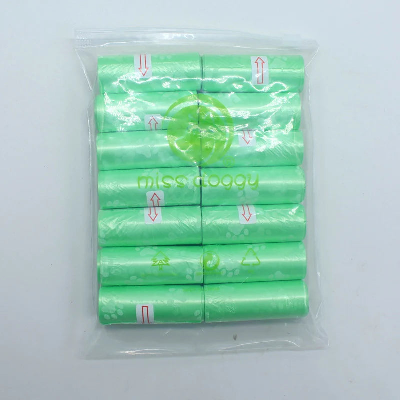 A pack of 14 rolls of green dog waste bags with dispensers is shown in a clear plastic bag.