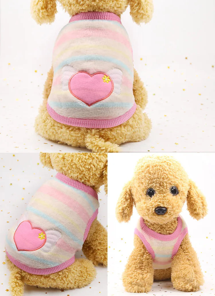 A fluffy yellow dog wearing a pink and blue striped fleece puffer vest with a heart design.