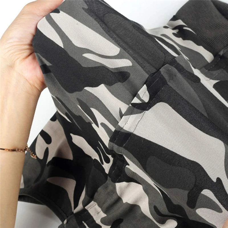 A close-up of a black and gray camouflage breathable pet recovery suit being held by a hand.