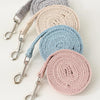 A stack of pet leash harnesses in various neutral tones including gray, beige, and blue.