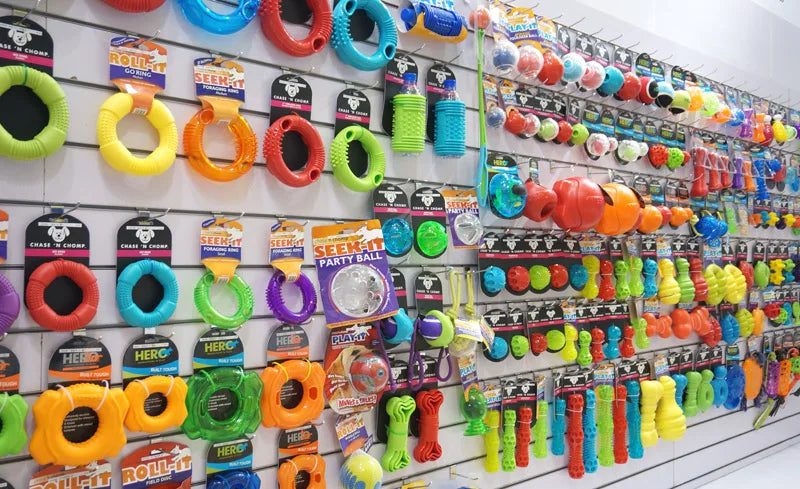 Exhibición de diversos juguetes de perro rebotantes y chirriantes en diferentes colores y formas.