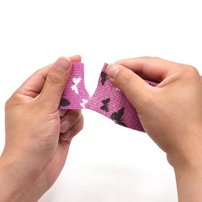 Hands are applying a pink and black patterned self-adhesive elastic bandage tape to a finger.