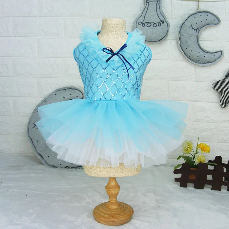 A light blue sequined princess dress for a puppy displayed on a mannequin against a white brick wall.