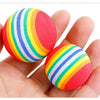 A hand holds a colorful, striped catnip chew toy plush with red and green accents.