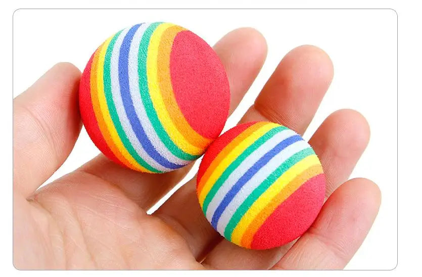 A hand holds a colorful, striped catnip chew toy plush with red and green accents.