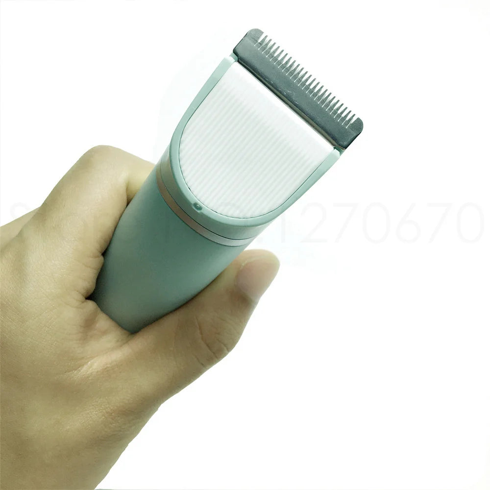 A hand holds a light green pet grooming trimmer with a silver comb attachment.