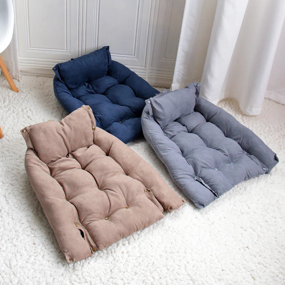 Three plush pet sofa beds in navy blue, gray, and beige are displayed on a white carpet.