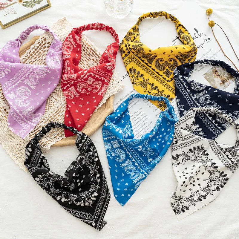 A collection of colorful bohemian paisley triangle head scarves in various patterns and fabrics.