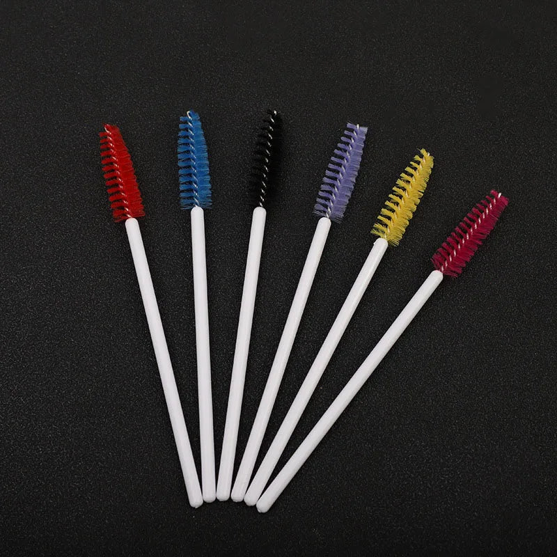 A collection of seven disposable eyelash brushes in various colors including red, blue, black, purple, yellow, and pink.