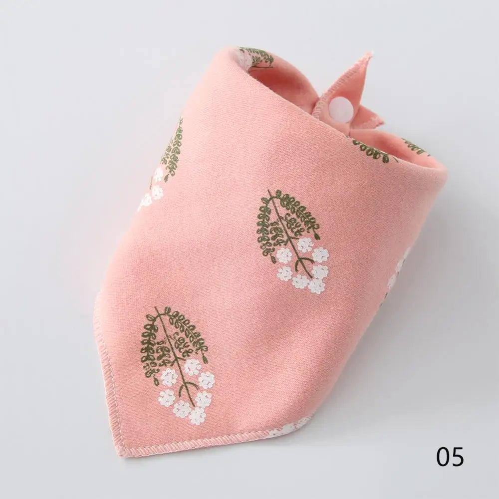 A pink cotton pet bandana with a green leaf and white flower pattern.