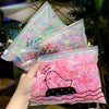 A hand holds a clear plastic bag filled with colorful elastic hair bands for girls.