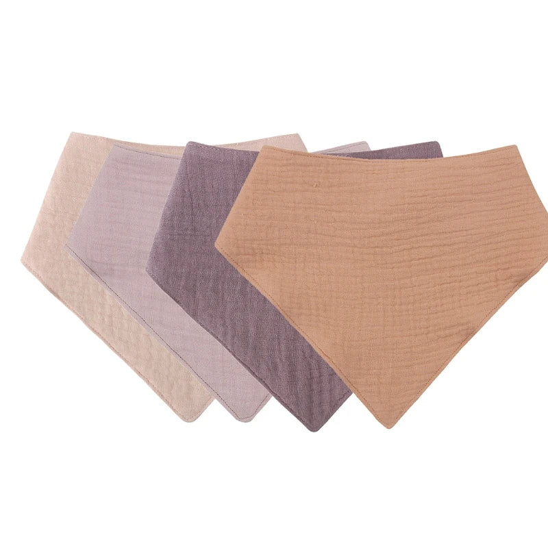 A stack of three soft cotton baby bibs in shades of beige and gray.