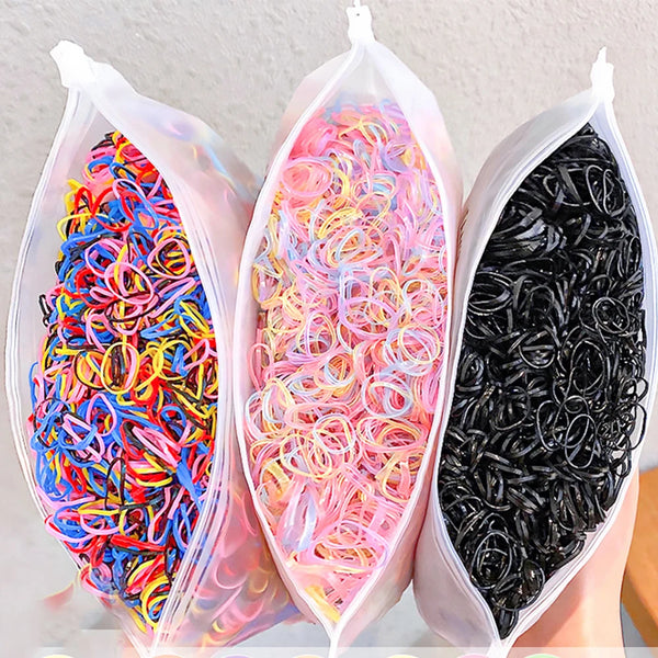 Three clear bags filled with colorful disposable elastic hair bands for girls in red, pink, and black.