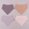 Three soft cotton baby bibs in lilac, peach, and pink shades displayed on a light gray background.