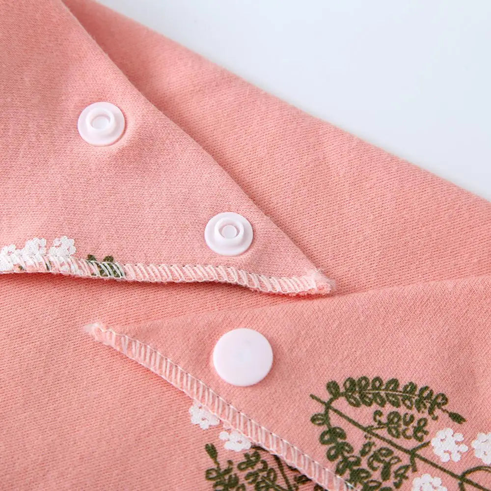 A close-up of a pink cotton pet bandana with white stitching and round buttons.