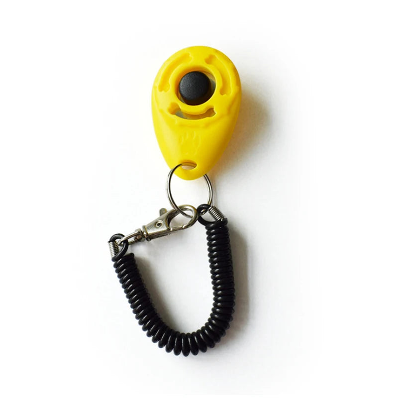 Yellow pet training clicker with a black eye and a metal wrist strap attached.