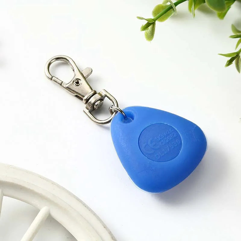 A blue waterproof LED pet collar light tag attached to a metal clasp, resting on a white surface.