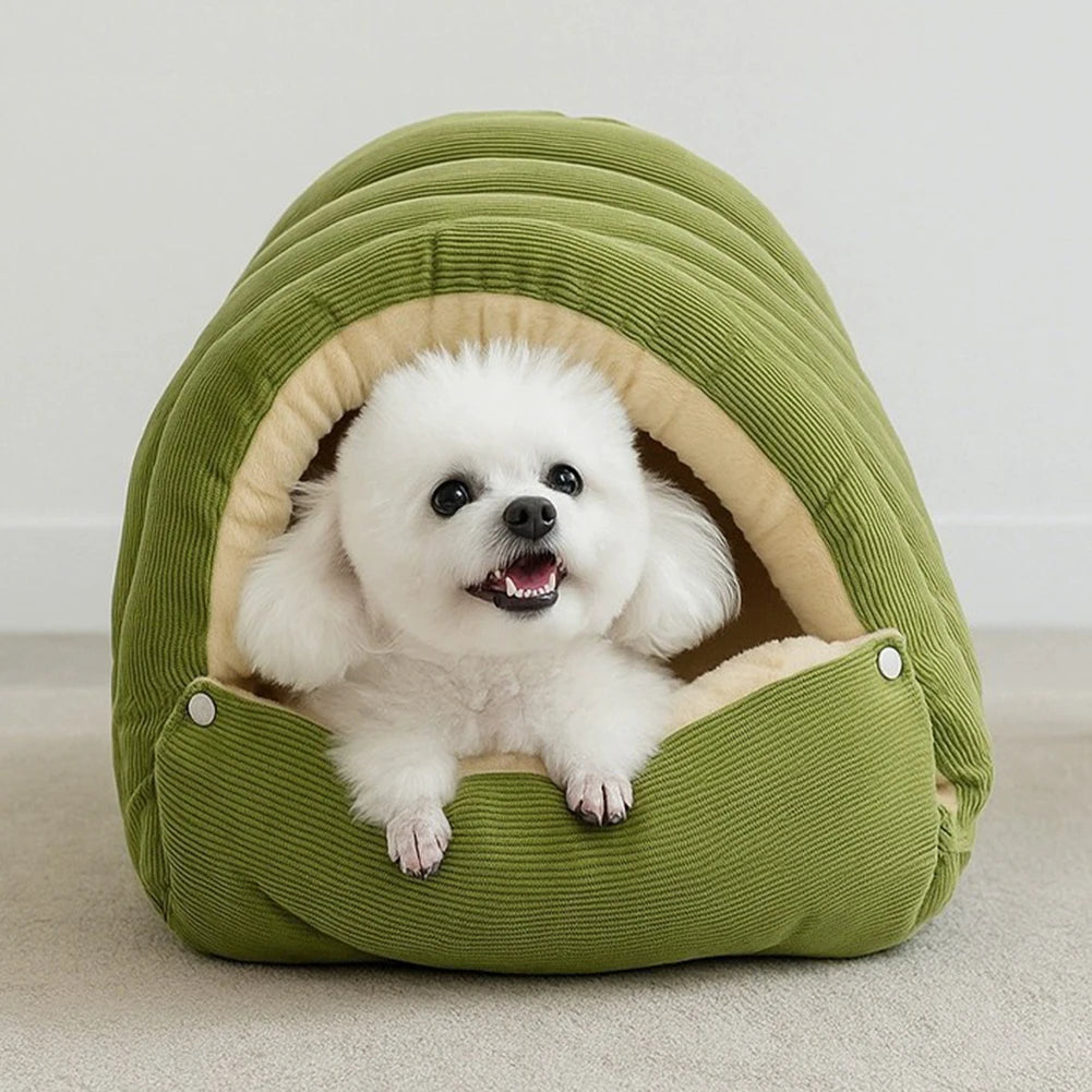 A fluffy white dog is resting inside a green plush cat cave bed with a removable beige cover.