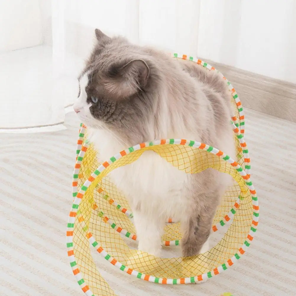 A fluffy gray and white cat is playing inside a yellow mesh foldable cat hunting tunnel on a light-colored floor.