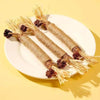 A plate holds several natural wooden teething sticks for cats with straw-like ends.