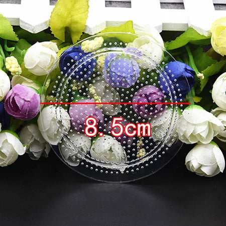 A clear petri dish filled with colorful Hama beads and tweezers, surrounded by fresh flowers.