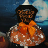 A black dress for a dog featuring gold lettering and an orange tulle skirt with silver skull details.