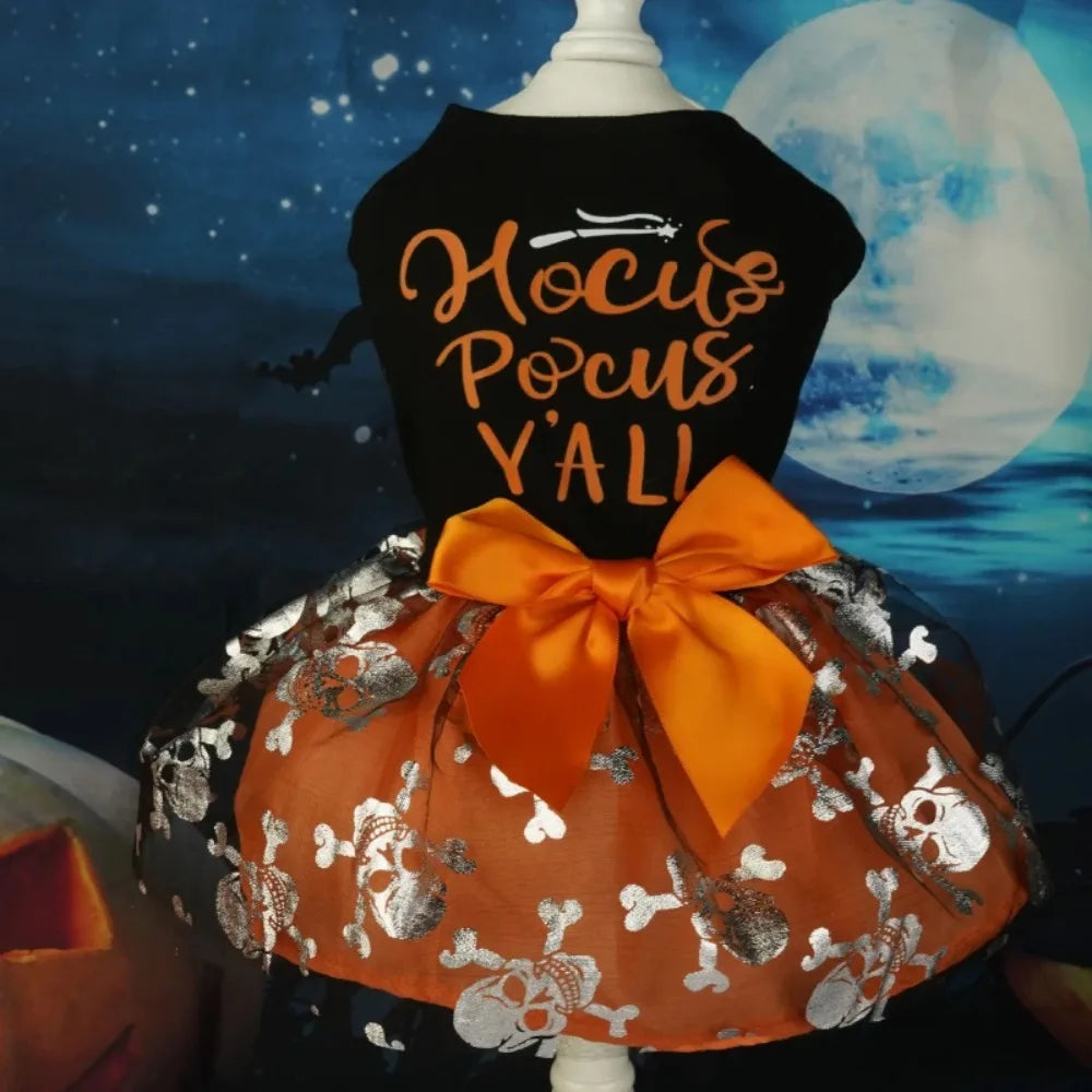 A black dress for a dog featuring gold lettering and an orange tulle skirt with silver skull details.