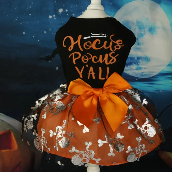A black dress for a dog featuring gold lettering and an orange tulle skirt with silver skull details.
