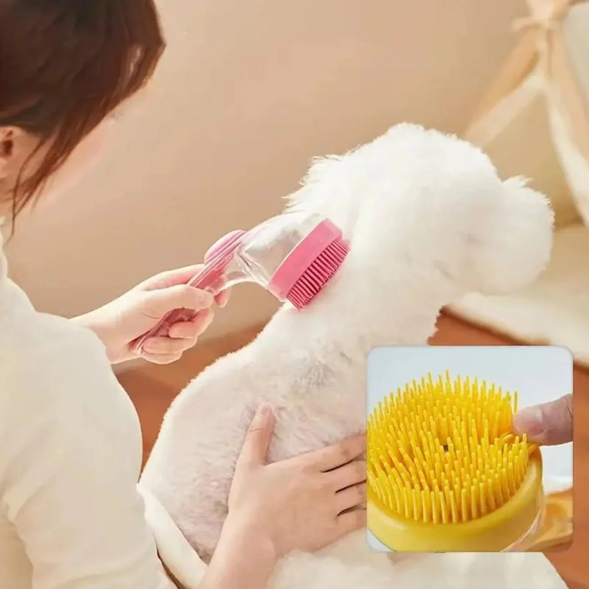 A person is using a pink silicone pet bath brush with a yellow shampoo dispenser on a white fluffy pet.